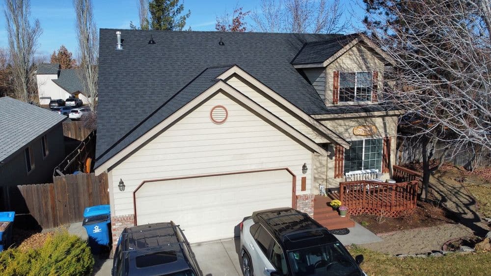 Aerial view of a two-story home with a garage, porch, and autumn landscaping.