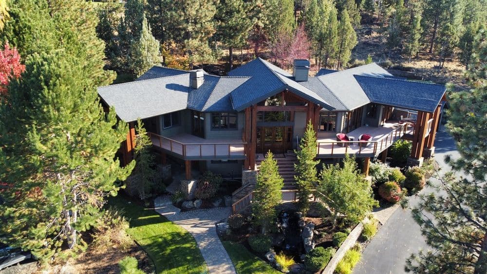 Aerial view of a modern house surrounded by trees and landscaped gardens.