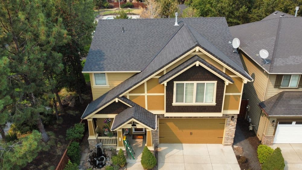 Aerial view of a modern two-story home with a landscaped yard and asphalt shingles.