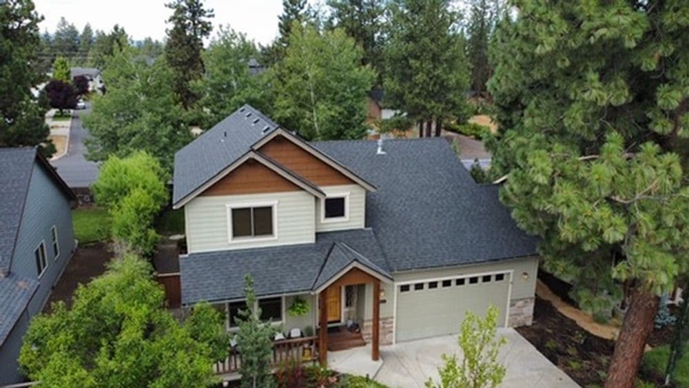 Aerial view of a modern two-story home surrounded by green trees and landscaping.