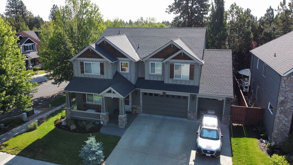 Aerial view of a modern two-story house with a landscaped yard and a parked car.
