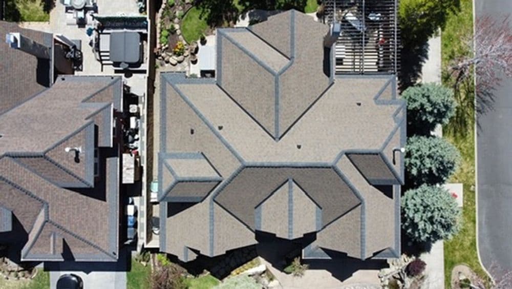 Aerial view of a residential roof showcasing multiple peaks and surrounding landscaping.