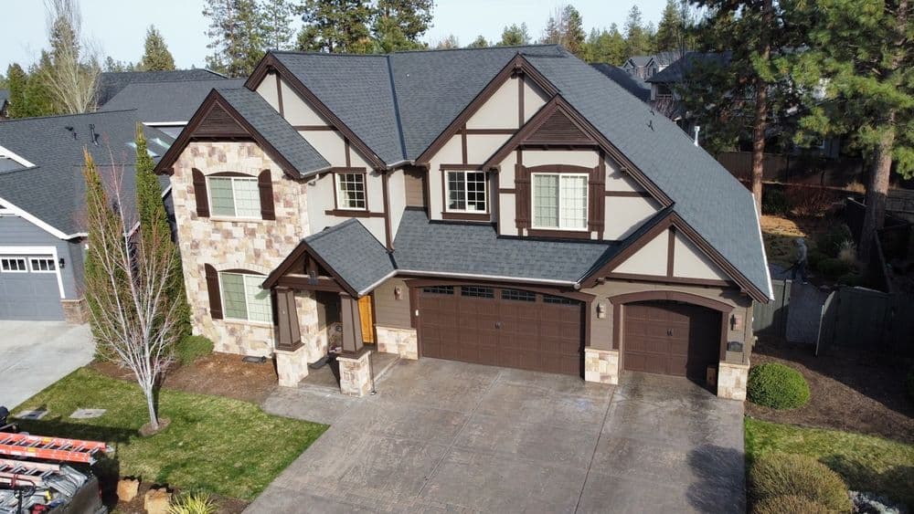 Elegant two-story home with stone accents and a symmetrical design, surrounded by lush greenery.