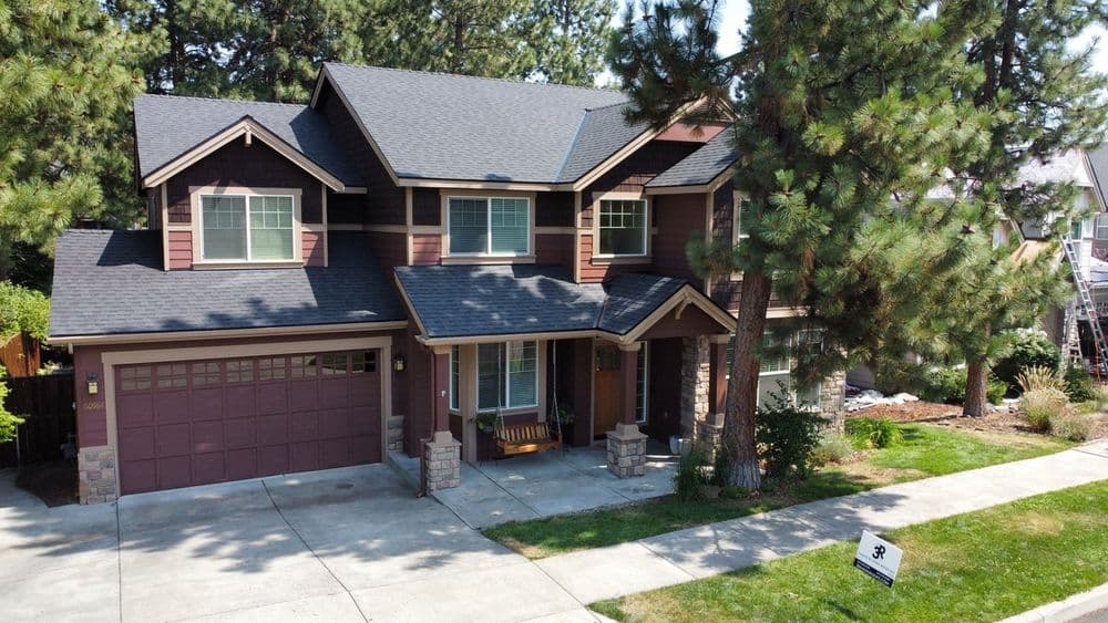 Two-story suburban home with a landscaped yard and attached garage under clear blue skies.