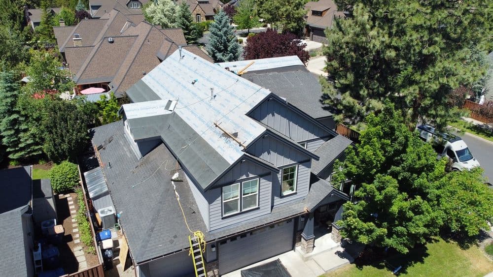 Aerial view of a home with a new roof under construction in a suburban neighborhood.