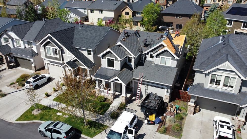 Aerial view of residential neighborhood with homes under roof construction and parked vehicles.