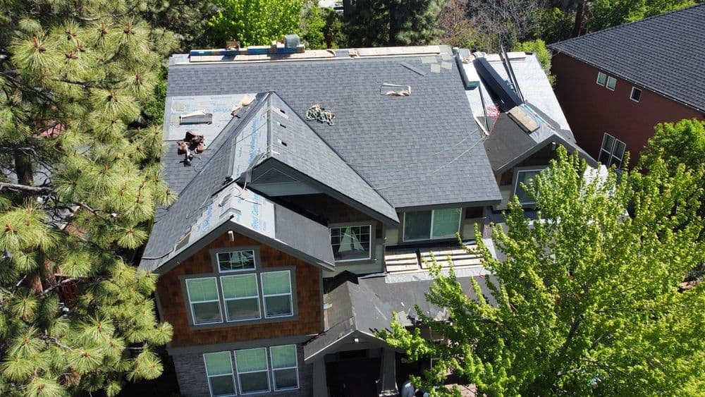 Aerial view of a newly roofed modern home surrounded by lush greenery.